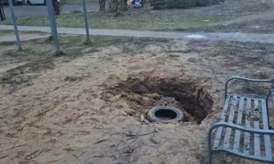 Яма с покрышкой на месте детской площадки рядом со скамейкой