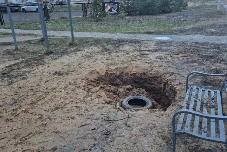 Яма с покрышкой на месте детской площадки рядом со скамейкой