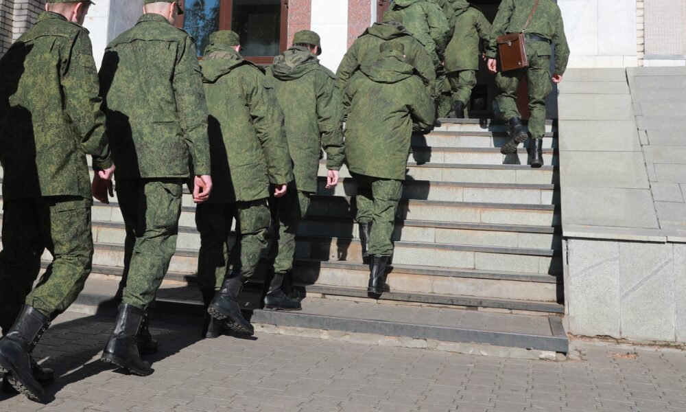 Военнослужащие в зеленой форме поднимаются по ступеням здания