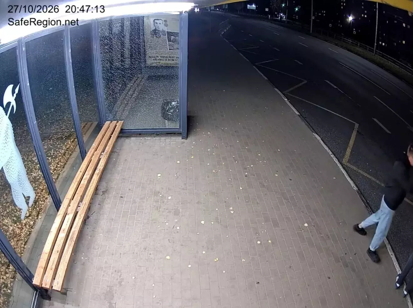 Разбитое стекло остановки и осколки на тротуаре ночью