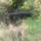 Ручей в зарослях травы под чёрной трубой
