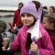 Девочка держит стакан с мальком сазана у берега Волги