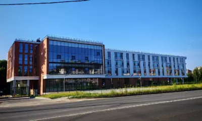 Современное здание школы с большими окнами у городской дороги