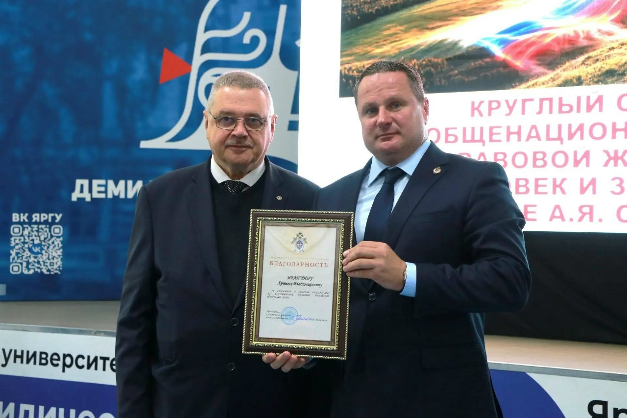 Сотрудник СК России вручает благодарность представителю Ярославского государственного университета