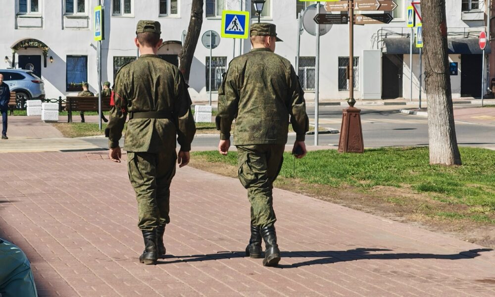 Двое солдат в военной форме идут по городской улице