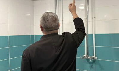 Мужчина осматривает душевую с открытыми трубами и смесителем