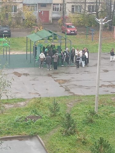 Группа школьников собралась у тренажёров на спортплощадке во дворе жилого дома
