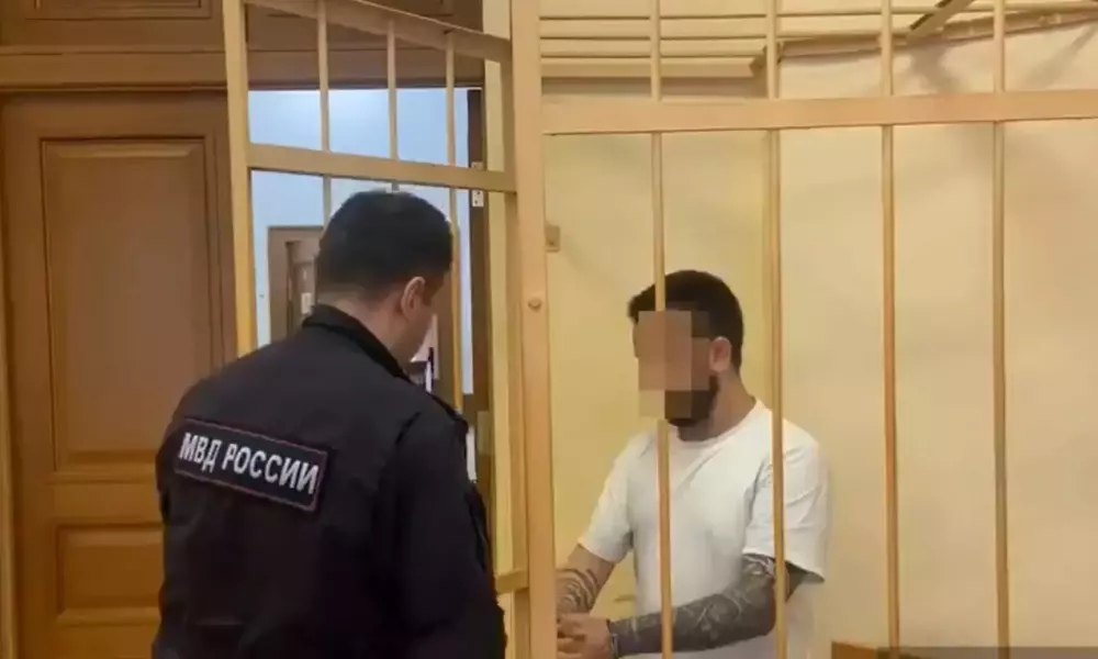 Подсудимый в клетке разговаривает с сотрудником МВД России в суде