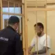 Подсудимый в клетке разговаривает с сотрудником МВД России в суде