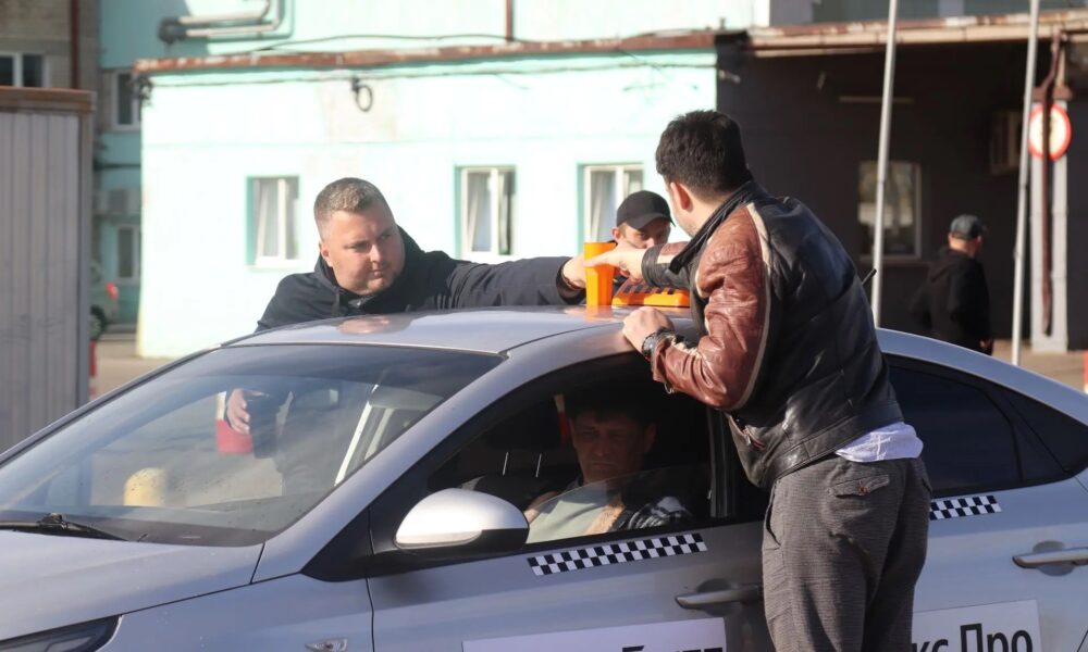 Таксист и мужчины ставят стаканы с водой на крышу автомобиля