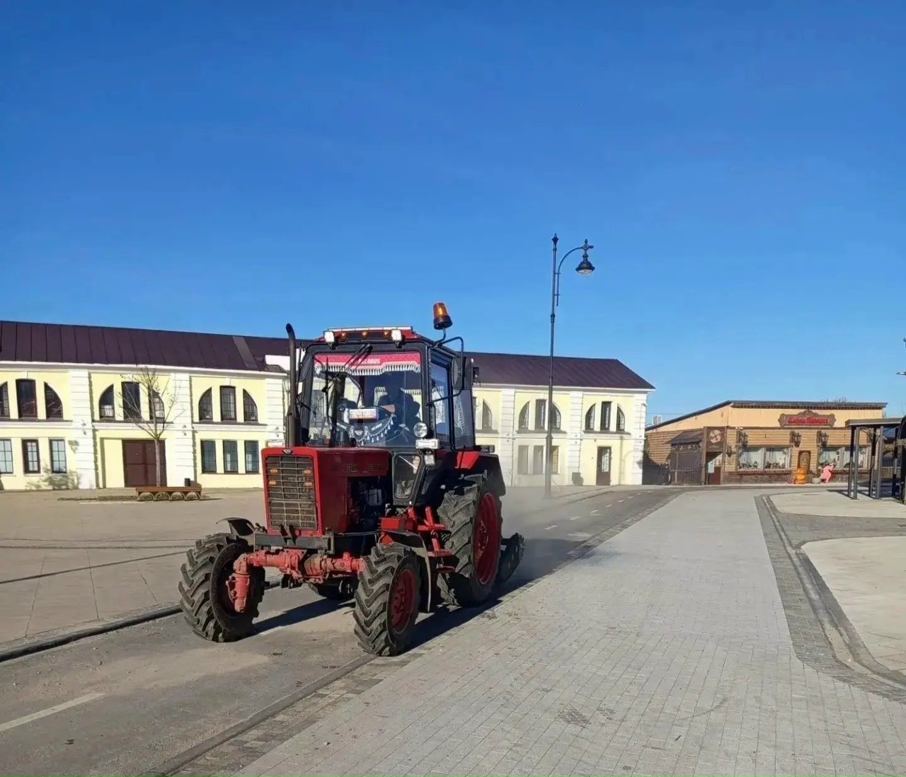 Трактор проводит уборку пешеходного центра на городской площади