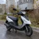Серебристо-чёрный скутер у жилого дома на мокрой дороге