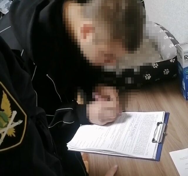 Судебный пристав оформляет документы с подростком за столом