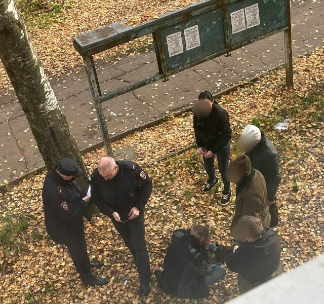 Сотрудники полиции беседуют с группой людей у информационного стенда осенью