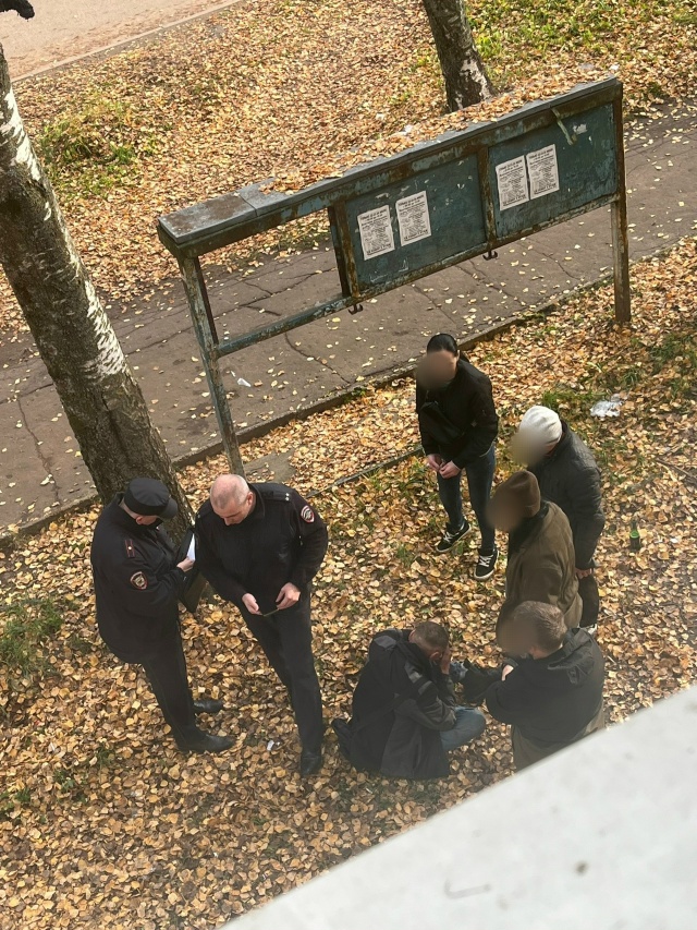 Сотрудники полиции беседуют с группой людей у информационного стенда осенью
