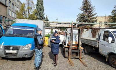 Сотрудники службы у грузовиков и погрузчика на территории завода