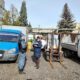 Сотрудники службы у грузовиков и погрузчика на территории завода