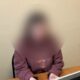 Пенсионерка с размытым лицом сидит за столом в помещении