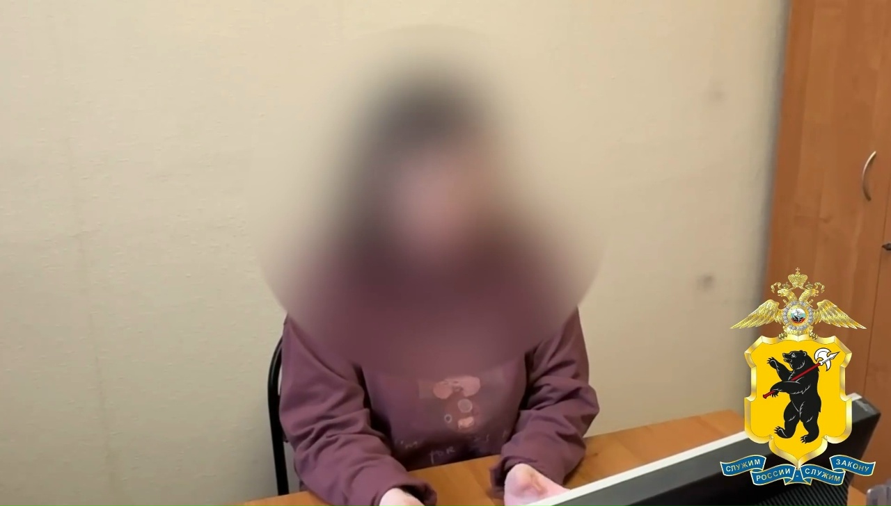 Пенсионерка с размытым лицом сидит за столом в помещении
